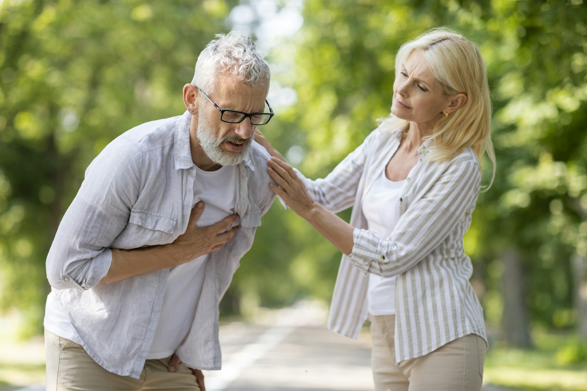 Mature Man Suffering Sudden Chest Pain While Walking With Wife In Park