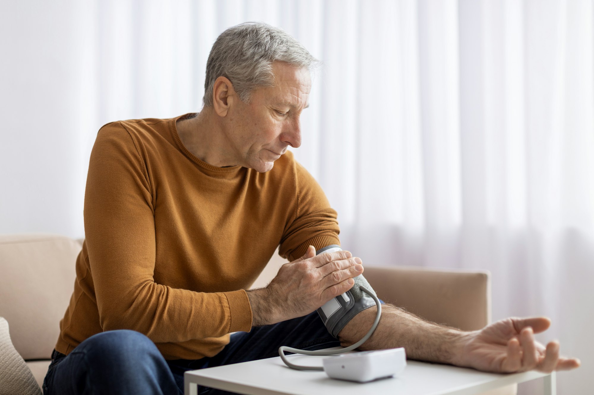 Pensioner using modern tonometer at home, experiencing hypertension